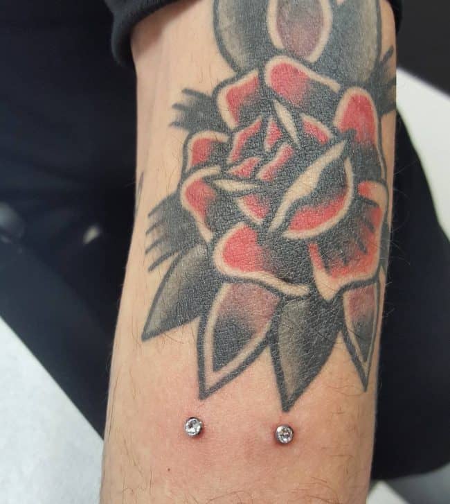 microdermal arm piercing and rose tattoo