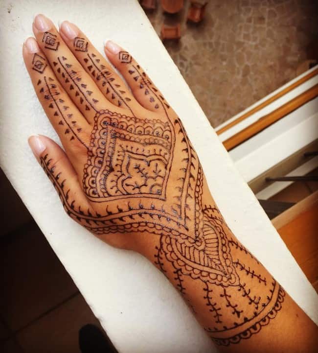 Premium Photo | Boho hand on the background of the magical happy sun with  mehendi. brown henna. natural picture.