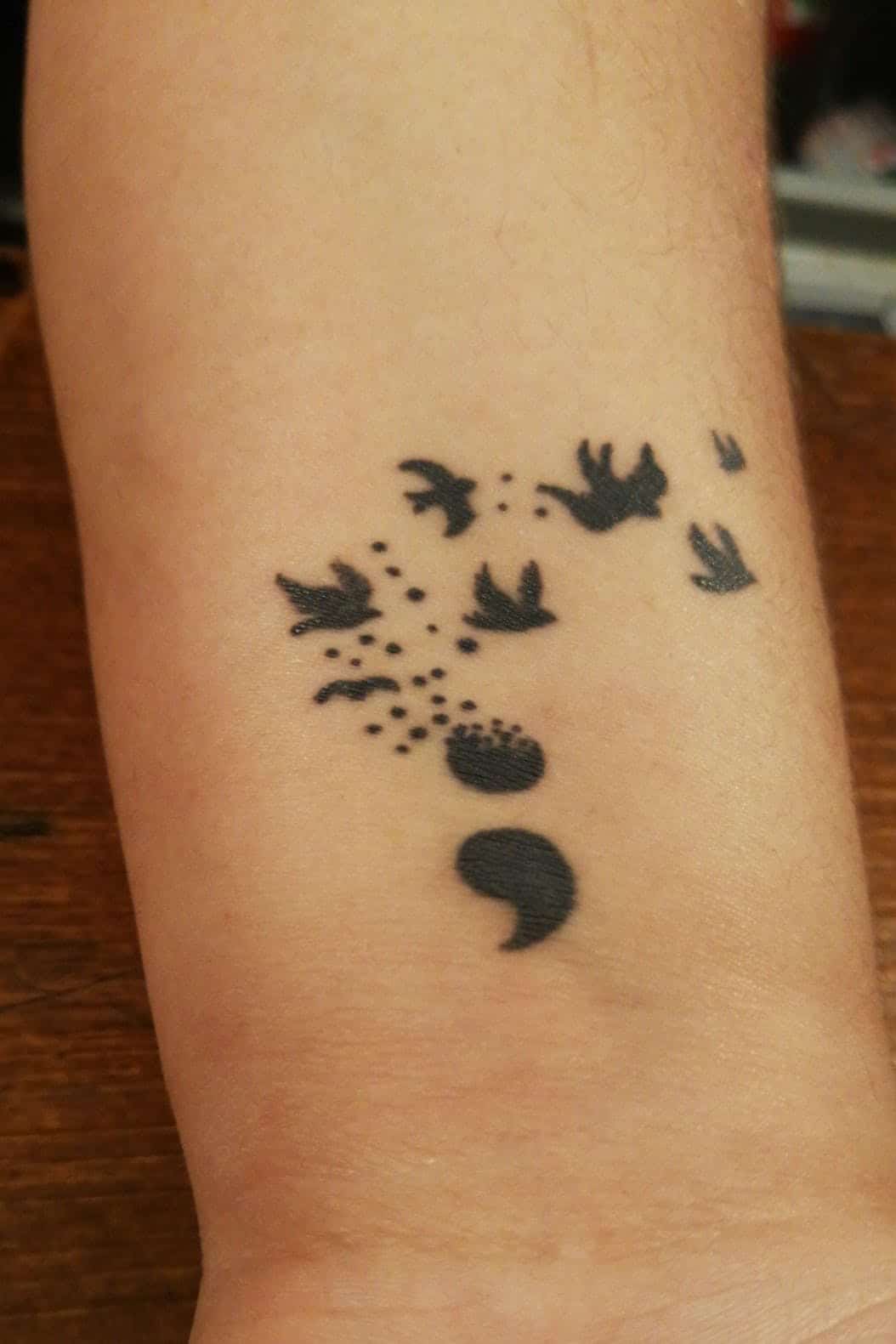 bird semicolon tattoo on arm