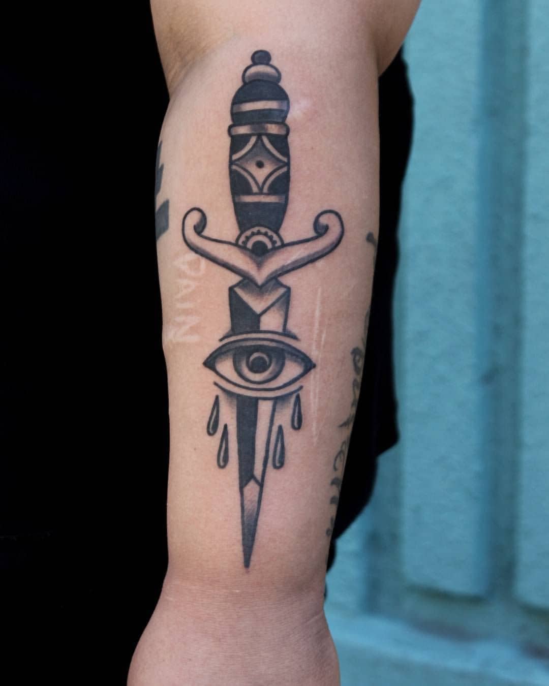 eye and dagger tattoo on arm
