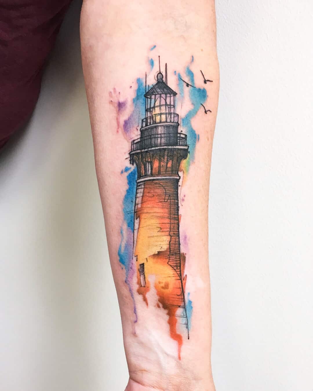 watercolor lighthouse tattoo on arm